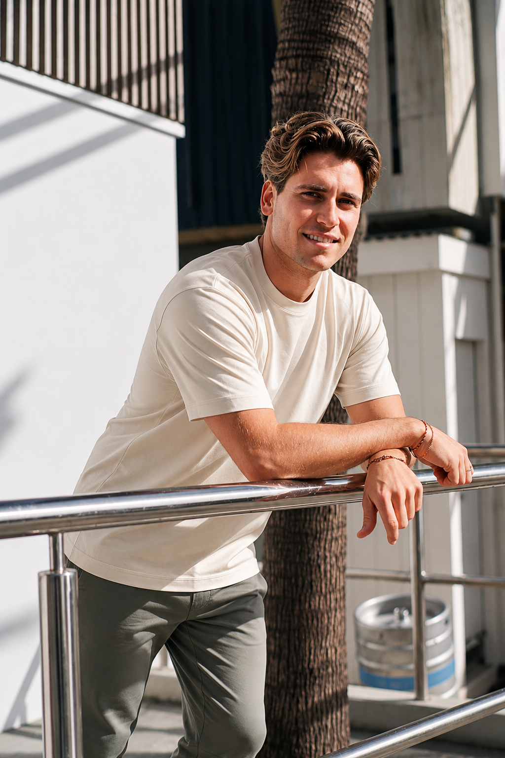 Man wearing white Premium Heavyweight Cotton T-Shirt, casual outdoor pose leaning on railing